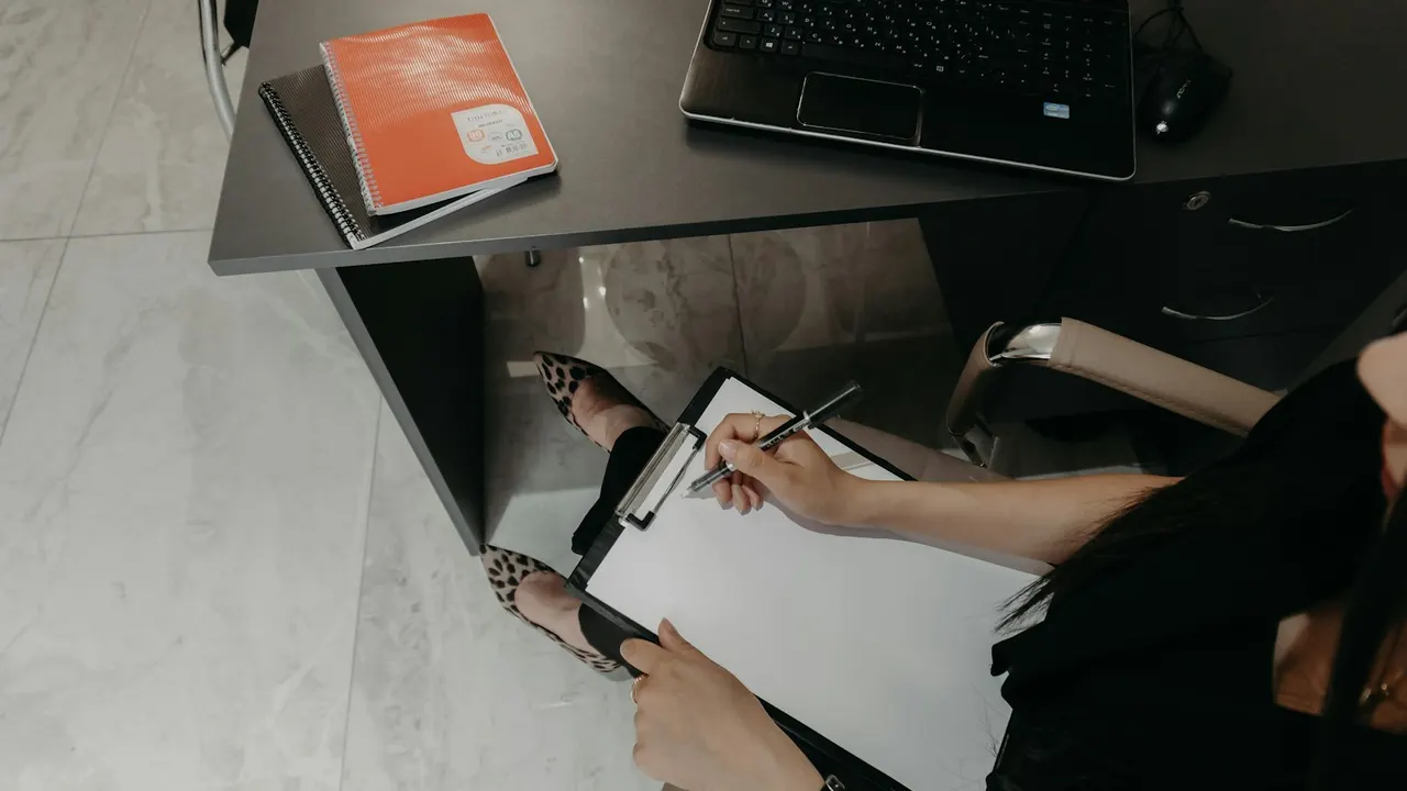 Lista impressa com itens marcados sobre uma mesa, ao lado de amostras de tecido e uma logomarca