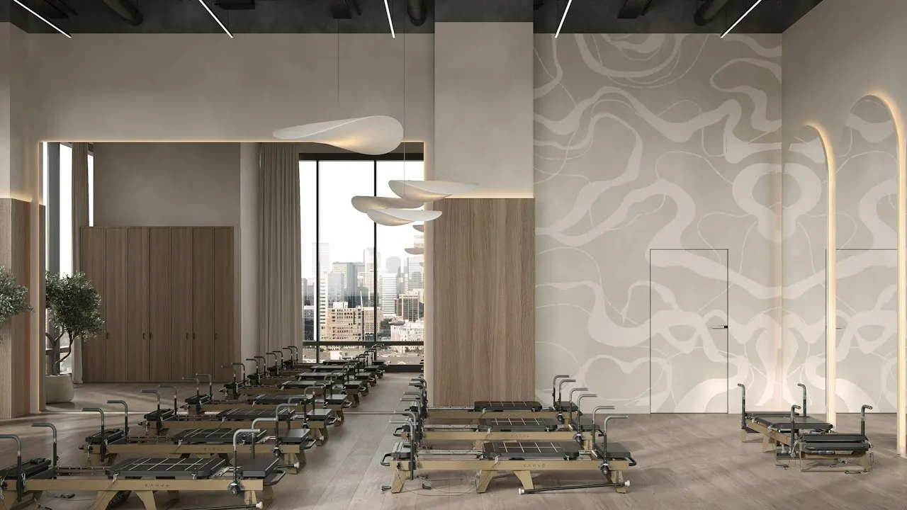 Estúdio de pilates amplo com aparelhos alinhados, piso de madeira e luz natural
